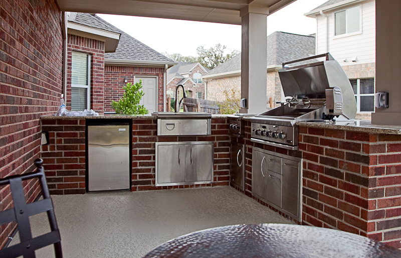 Brick Outdoor Kitchen with granite countertops, built-in grill, sink, and refrigerator