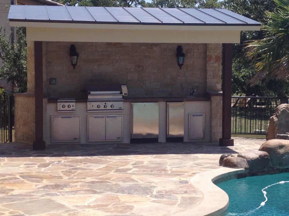 Outdoor kitchen and grilling station with metal roof cover and stone